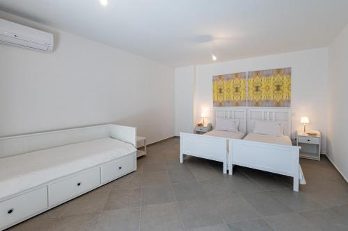 a white bedroom with two beds and two tables at Costa Bianca Villas in Koilás