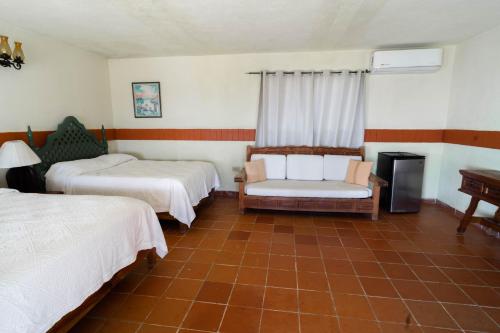 a room with two beds and a chair and a piano at Hotel Rancho Buenavista in Los Barriles