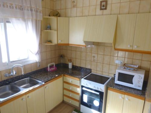 a small kitchen with a sink and a microwave at Exclusivo Chalet a Pie de Costa in Alcanar