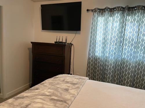 a bedroom with a bed and a dresser with a television at Bellissma Suite formerly known as Sweet Suite in Sooke