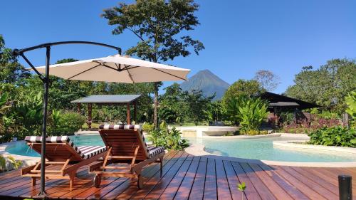 フォルトゥナにあるHotel Arenal Glampingのプールサイドのデッキ(椅子2脚、パラソル付)