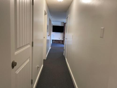 a hallway with white walls and a long hallway with white doors at Bellissma Suite formerly known as Sweet Suite in Sooke