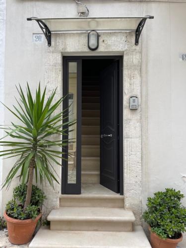 een zwarte deur op een wit huis met een plant bij Casetta Nobile in Ostuni