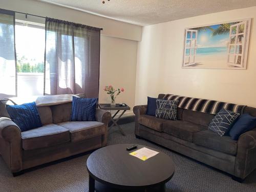 a living room with two couches and a table at Bellissma Suite formerly known as Sweet Suite in Sooke
