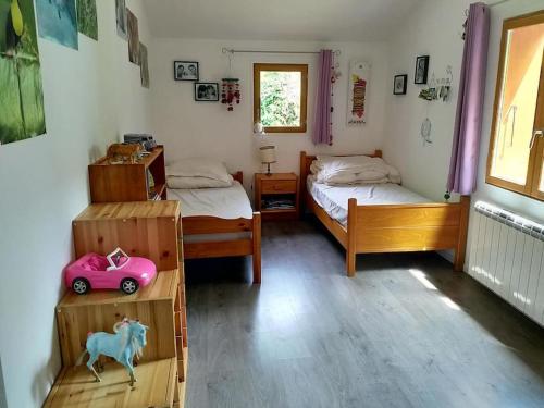 une chambre avec deux lits et une petite voiture rose à l'intérieur dans l'établissement Maison 8 pers, 4chbr,140m2,piscine, à Notre-Dame-de-Mésage