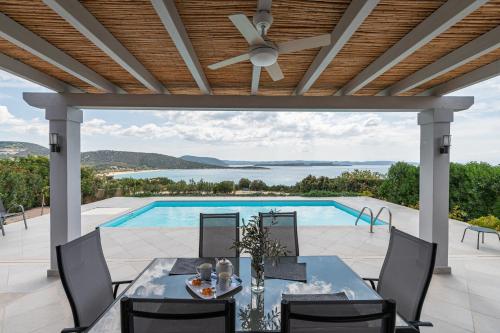 a patio with a table and chairs and a swimming pool at Costa Bianca Villas in Koilás