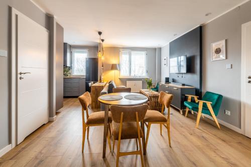 a dining room and living room with a table and chairs at G15 Apartment in Olsztyn