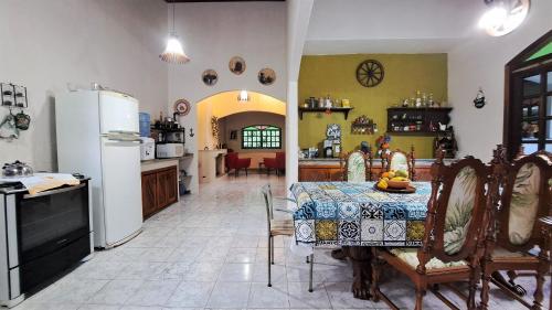 a kitchen and dining room with a table and refrigerator at Paradisíaco, piscina e churrasqueira em Guapimirim in Barreira