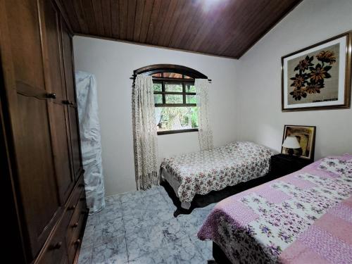 1 Schlafzimmer mit 2 Betten und einem Fenster in der Unterkunft Paradisíaco, piscina e churrasqueira em Guapi. in Guapimirim