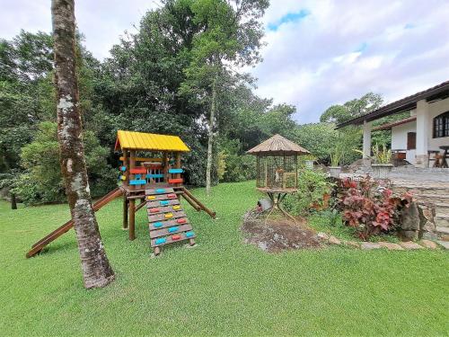 a playground with a slide and a play house at Paradisíaco, piscina e churrasqueira em Guapimirim in Barreira