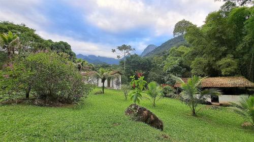 a green yard with houses and trees and mountains at Paradisíaco, piscina e churrasqueira em Guapimirim in Barreira