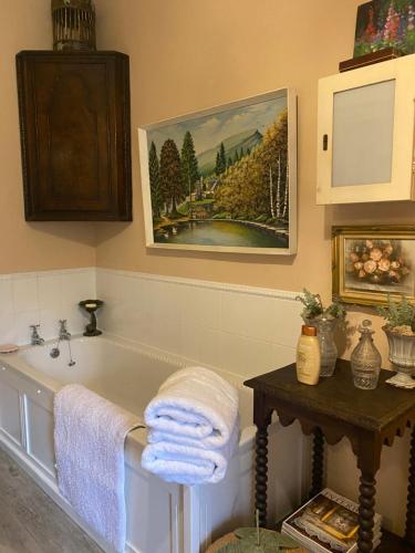 uma casa de banho com banheira e uma pintura na parede em Historic House in Beatrix Potter Village em Near Sawrey