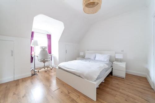 een witte slaapkamer met een wit bed en een spiegel bij 2 Bedroom Duplex Apartment in Londen