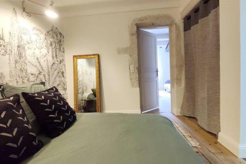 - une chambre avec un lit vert et un miroir dans l'établissement Uzès médiévale l'écrin d'Amalia, à Uzès