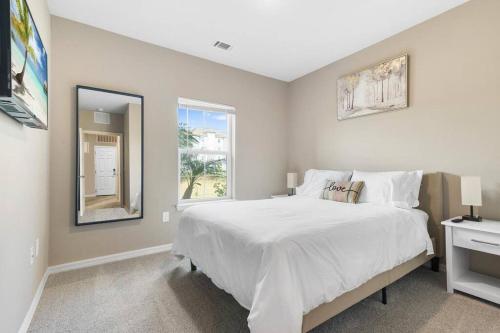 a white bedroom with a large bed and a window at Luxury 3 Bedroom/2 Bathroom Condo in Melbourne FL with Pool, Gym and Laundry in Melbourne