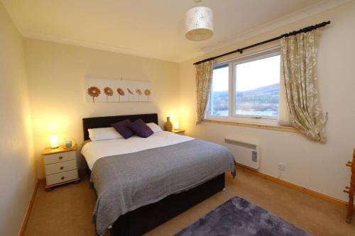 a bedroom with a large bed and a window at Rowan Cottage Highland retreat near Fort William in Spean Bridge