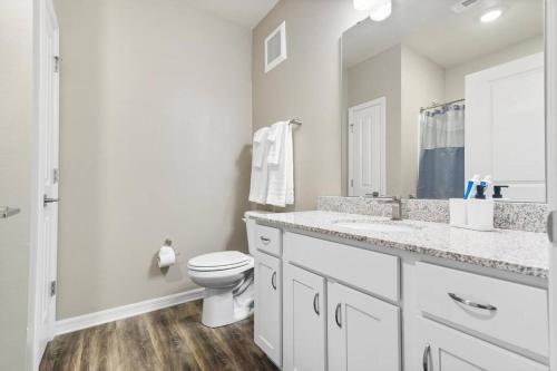 a white bathroom with a toilet and a sink at Luxury 3 Bedroom/2 Bathroom Condo in Melbourne FL with Pool, Gym and Laundry in Melbourne