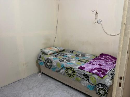 a small bed in a corner of a room at comfortable homeroom for upto 2 persons in Sharjah