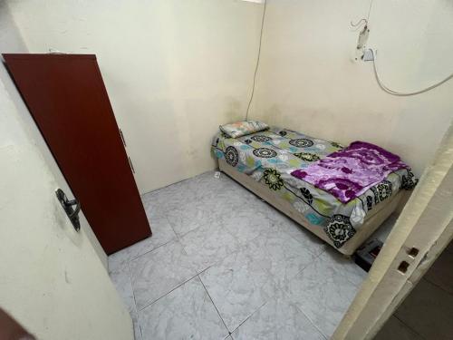 a small room with a bed in a corner at comfortable homeroom for upto 2 persons in Sharjah