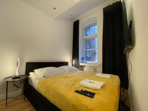 a bedroom with a bed with a yellow blanket and a window at Central Rooms Apartment in Toruń