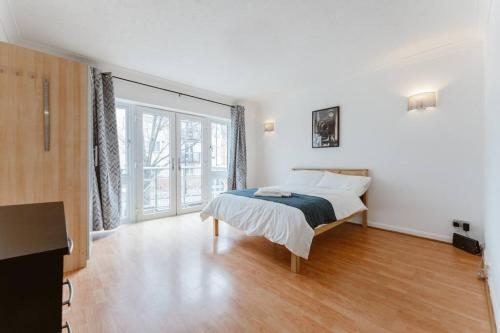 a white bedroom with a bed and a large window at Up to 4 people, Room In a Share house next to London Bridge in London