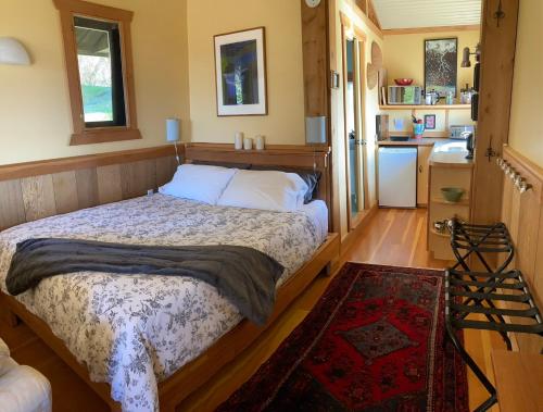 a bedroom with a large bed and a kitchen at Blitz Beach House Oceanside Suite in Powell River