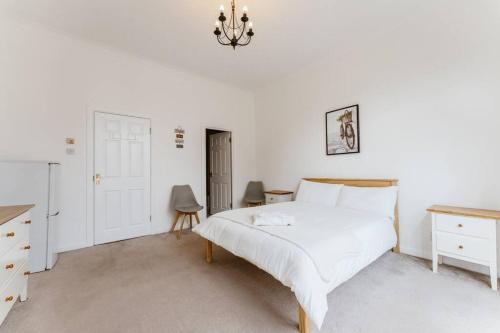 a white bedroom with a bed and a chandelier at Spacious Ensuite Room Near Top Tourist Attractions in London