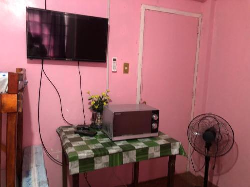 a room with a table with a tv on a pink wall at LP Madriaga Private Apt fully furnished w/Balcony in Ayusan Norte