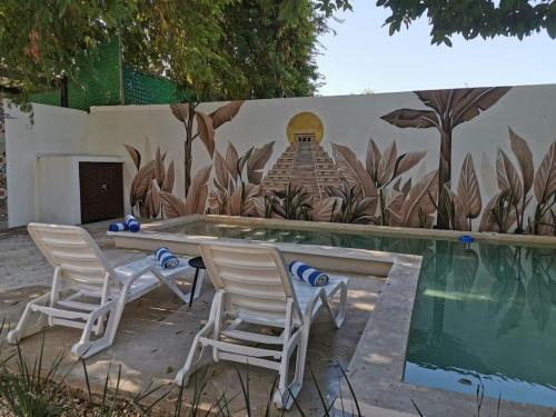 two chairs and a table next to a swimming pool at Casa Blanca in Mérida