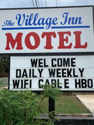 um sinal para o motel Village Inn com um sinal em The village inn em Denham Springs