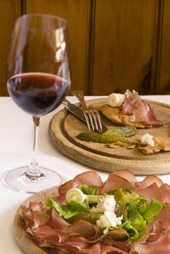a table with a glass of wine and a pizza at Hotel Garni Lichtenau in Schenna