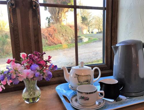 una mesa con tazas y un jarrón de flores y una ventana en The Stable en Saint Clether