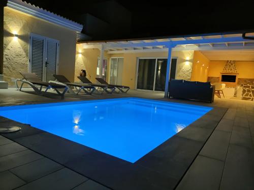 uma piscina iluminada à noite em villa bonita em Corralejo