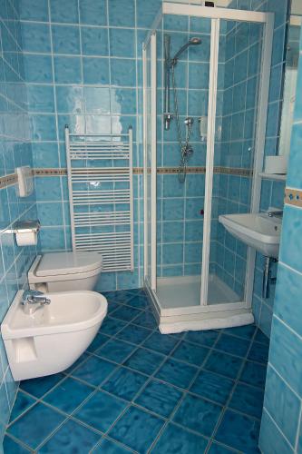 a blue tiled bathroom with a toilet and a shower at Hotel Capital in Cupra Marittima