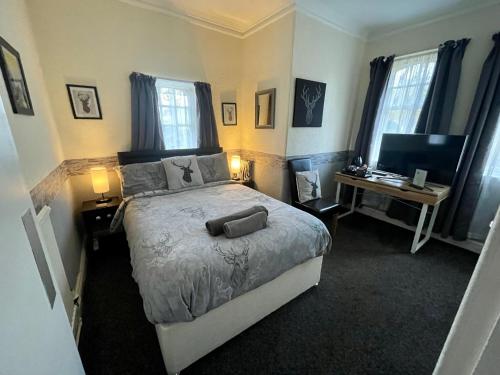 a bedroom with a bed and a desk with a computer at Navaar House Hotel in Penicuik