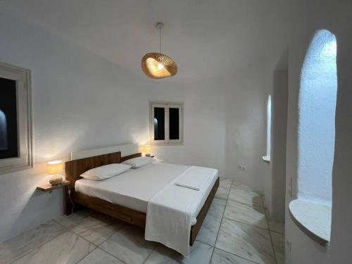 una camera bianca con letto e lampadario di Villa Cybele Tinos a Kardhianí