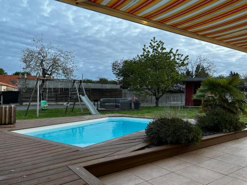 a swimming pool in a backyard with a playground at Maison familiale 4 chambres avec jardin et piscine in Saint-Aignan-Grand-Lieu