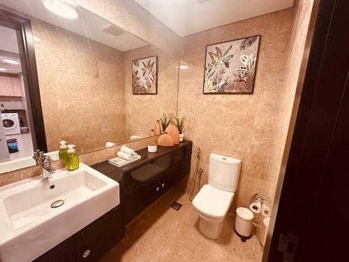 a bathroom with a sink and a white toilet at Ocean Terrace Apartment in Abu Dhabi