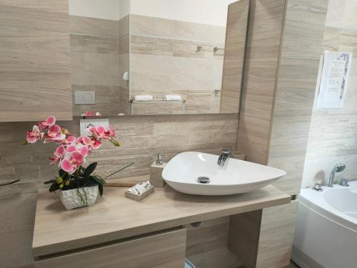 un bagno con lavandino e fiori su un bancone di Appartamento con idromassaggio e super vista 