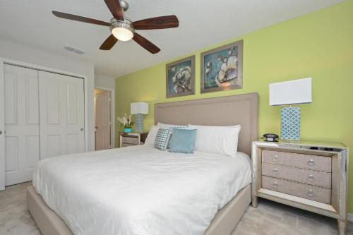 um quarto com uma cama branca e uma ventoinha de tecto em Four Bedrooms Townhouse 5102 em Kissimmee