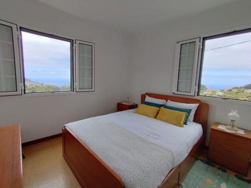 een slaapkamer met een bed en 3 ramen bij Terra Batista house in Porto da Cruz