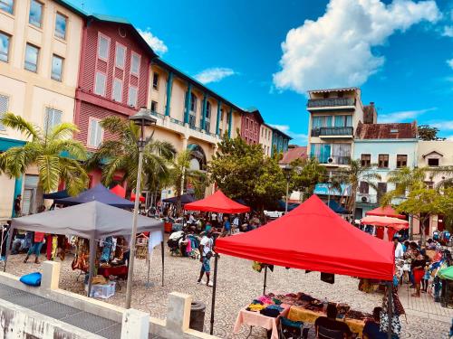 eine Straße mit Tischen, roten Sonnenschirmen und Gebäuden in der Unterkunft FABULEUX STUDIO Centre ville Fort De France Martinique CAPITALE in Fort-de-France