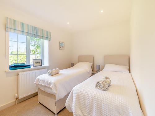 two beds in a room with a window at The Cottage Middle West Water in Axminster