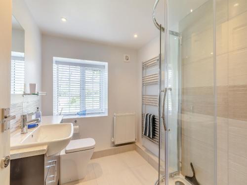 a white bathroom with a shower and a sink at The Cottage Middle West Water in Axminster
