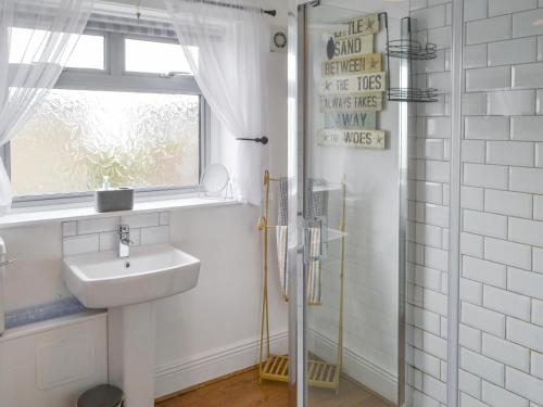 a bathroom with a sink and a window and a shower at Beas Cottage in Cresswell