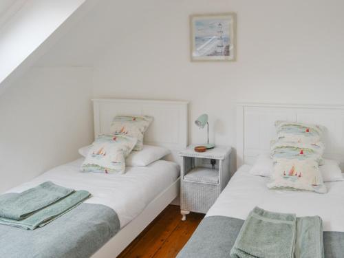 two twin beds in a room with white walls at Beas Cottage in Cresswell