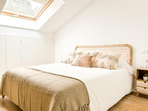 Dormitorio blanco con cama con sábanas y almohadas blancas en El Olivo by ALÔGA en Corcubión