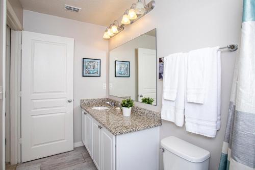 La salle de bains blanche est pourvue d'un lavabo et d'un miroir. dans l'établissement Four Bedrooms Townhome 5108K, à Kissimmee