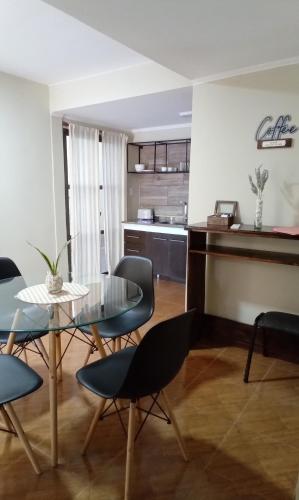 comedor y cocina con mesa de cristal y sillas en Loft/Apart Michel Iguazu en Puerto Iguazú