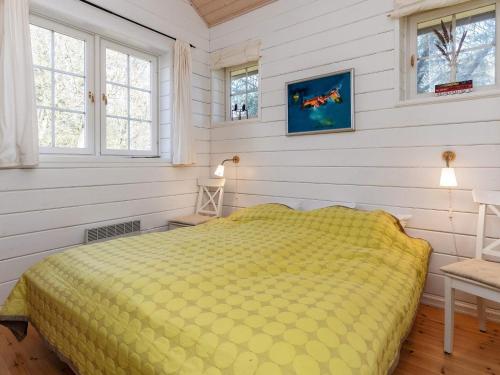 uma cama amarela num quarto com paredes e janelas brancas em Holiday home Løgstør IX em Løgstør